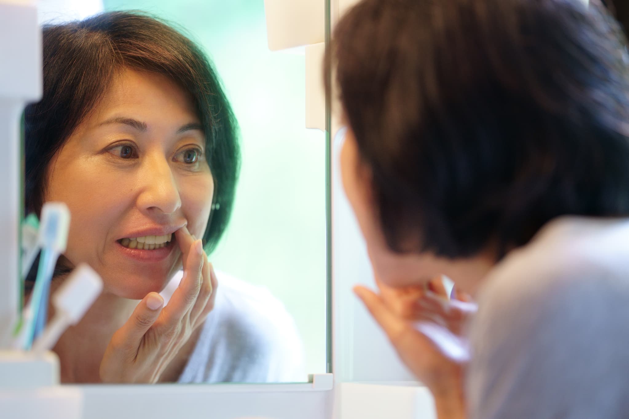 歯周病になった歯ぐきを鏡を見る女性