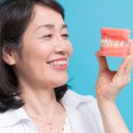 入れ歯を手にして笑顔を見せる女性