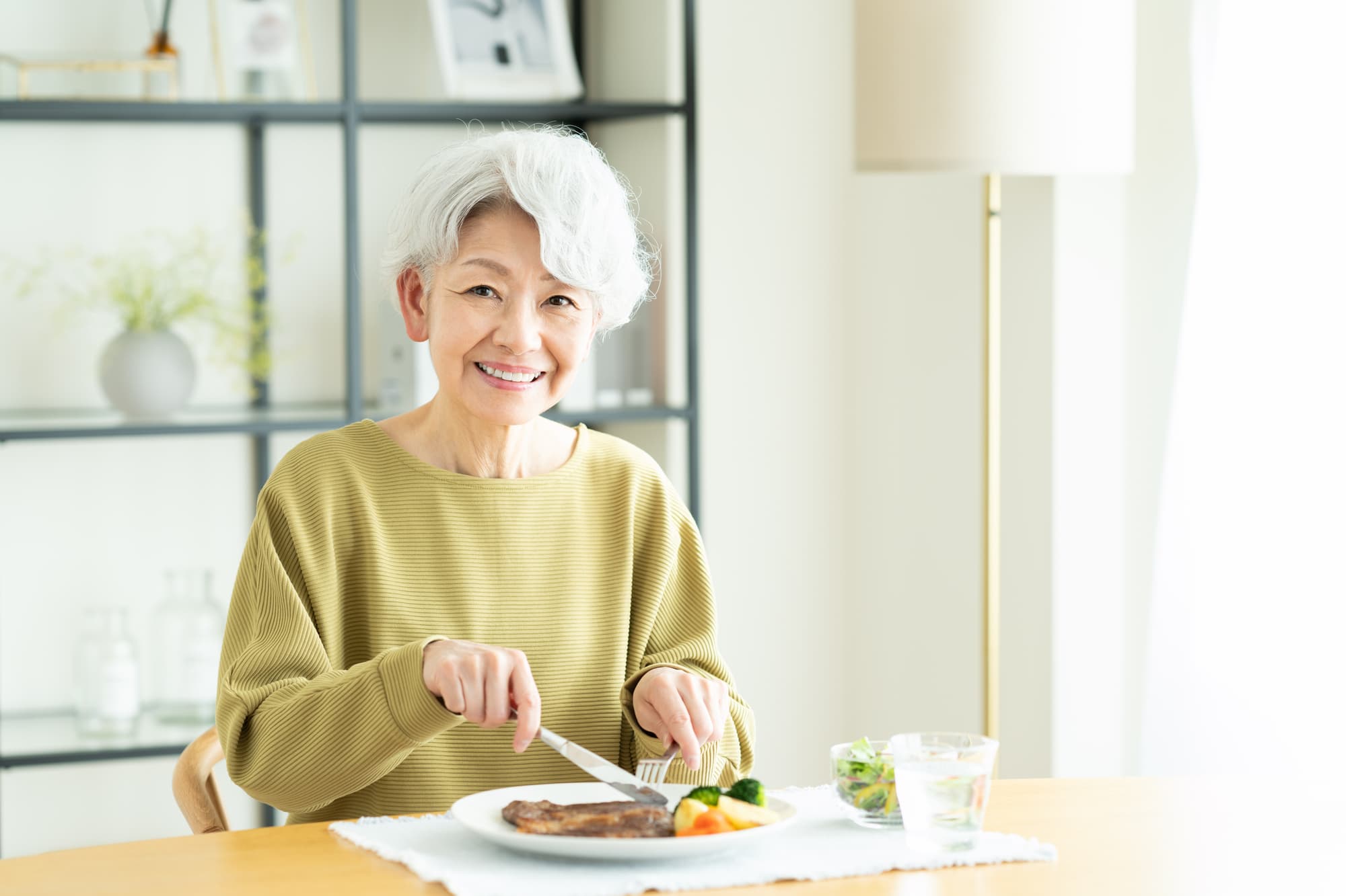 抜けたインプラントを再治療して食事を楽しむ女性