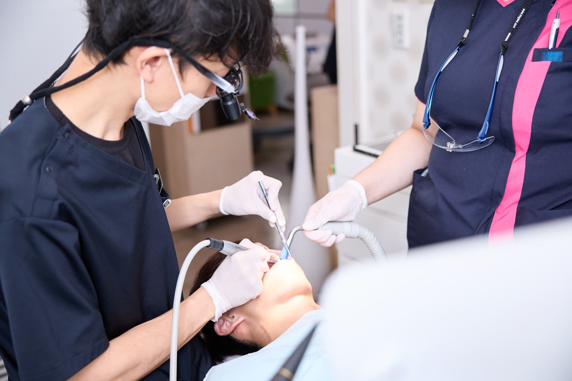 フラップ手術をする歯科医師とアシスタントする歯科衛生士