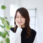 インビザライン矯正中に痛みを感じて頬を抑える女性