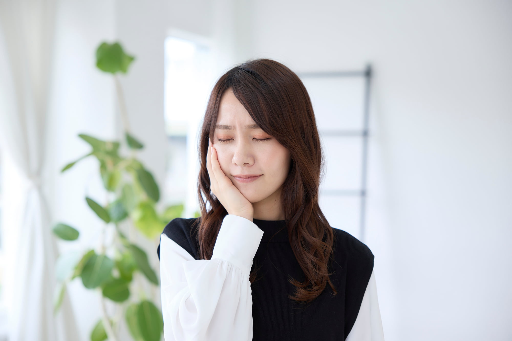 インビザライン矯正中に痛みを感じて頬を抑える女性